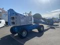 A blue 1997 Genie S-65 4X4 lift with a long articulated arm and large rubber tires designed for elevated work tasks