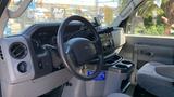 Interior view of a 2013 Ford Econoline van showing the dashboard steering wheel and console with controls and cup holders