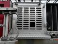 Close-up of a silver metallic panel with diamond texture featuring a square opening and ventilation slots on a fire truck