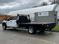 A 2017 Ford F-550 flatbed truck with a black bed and white cab featuring a protective grille on the rear and a cargo box mounted on the back