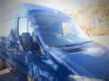 Blue 2017 Mercedes-Benz Sprinter van with a large windshield and side mirrors visible in the foreground