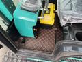 A 2024 AGT Industrial Green QH13R Mini Excavator with a control panel and storage compartments inside the operator's cabin