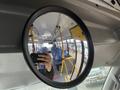 A circular mirror reflecting the interior of a bus with blue seats and poles visible in the background