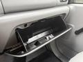 A gray dashboard of a 2006 Ford F-450 with an open glove compartment revealing storage space and a latch