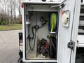 A 2017 Ford F-550 service truck with an open compartment showing a pump, hoses, and various equipment inside