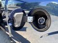 A 2015 Ford F-150 fuel door with a black cap and fuel nozzle inserted