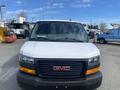 A 2022 GMC Savana van is shown from the front with a white exterior and a black grille featuring a red GMC logo