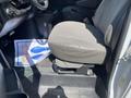 A 2012 Chevrolet Express driver's seat with a grey fabric cover and a visible floor mat featuring a graphic design