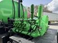 A green engine with multiple valves and pipes mounted on a black platform resembling a truck's machinery