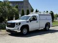 A white 2022 GMC Sierra 1500 pickup truck with a utility cap and roof racks parked on a concrete surface