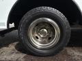 Close-up of a tire on a 2017 Ford Econoline showing a chrome wheel with six bolts and an all-terrain tread pattern
