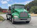 A green 2013 Kenworth T370 truck with a silver grille and chrome bumpers is parked on a street facing forward