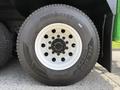 Close-up of a heavy-duty tire mounted on a white wheel showing "IRON FIST" tire branding and tread design with visible bolts on the wheel hub