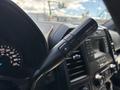 Close-up of a 2016 Ford F-150 steering wheel control lever with buttons for adjusting drive modes and a digital display in the background