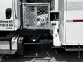 A 2012 Freightliner M2 106 with a metallic rear step and a side compartment equipped with a fuel tank and other mechanical elements