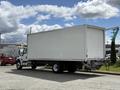 A white 2022 International MV607 box truck parked on a paved area with a large cargo area and a rear lift gate