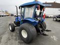 A blue 2007 New Holland TN70A tractor with a cab and large rear tires parked on a lot