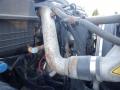 Close-up of the engine compartment of a 2014 International Durastar showing pipes wires and components with some rust on the metallic parts