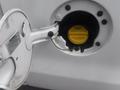 A 2015 Chevrolet Silverado 1500 with its fuel door open revealing the yellow fuel cap inside