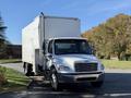 A 2011 Freightliner M2 106 truck with a white box trailer is parked with its cab facing forward and the driver's side door open