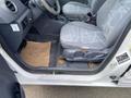A 2013 Ford Transit Connect interior showing the driver's side with gray upholstery seats and a brown floor mat