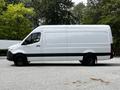 A 2023 Mercedes-Benz Sprinter van in white with a black trim viewed from the side showcasing its long cargo area and large wheels