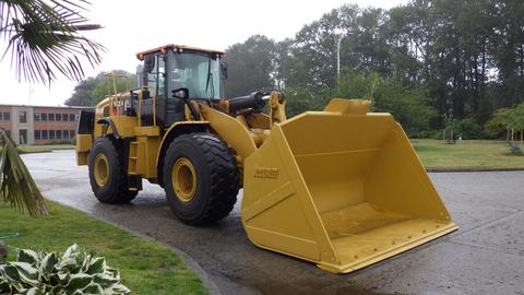 A 2019 Caterpillar 972M XE wheel loader with a large yellow bucket positioned in front ready for excavation or lifting tasks