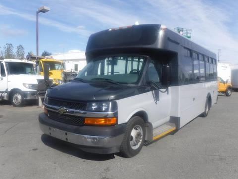 A 2017 Chevrolet Express bus with a black and white exterior featuring a front grille and large windows designed for passenger transport