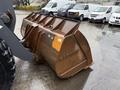 A close-up of a heavy-duty bucket attachment for a 2018 Doosan DL300-5 loader made of rusted metal with a distinctive curved shape and front tooth design