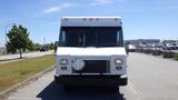 A white 2006 Ford Econoline commercial van with a large front grille and multiple orange roof lights parked on a road