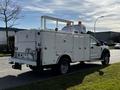 A 2018 Ford F-550 truck with a white utility body featuring multiple lockable compartments and an elevated platform with amber warning lights
