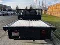 A 2017 Chevrolet Silverado 3500HD flatbed truck viewed from the rear with a metal mesh backup guard and a wooden bed surface