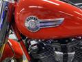 A 2024 Harley Davidson Fat Boy motorcycle with a shiny red body and chrome accents including the Harley Davidson badge on the fuel tank