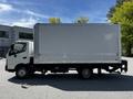 A 2018 Hino 195 box truck is parked, featuring a white cargo area with a roll-up door, black chassis, and front cabin visible on the driver's side