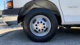 A silver alloy wheel from a 2011 Chevrolet Express featuring a central Chevrolet logo and dark tire tread