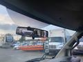 A 2017 Chevrolet Express seen from the driver's perspective with a rearview mirror reflecting other vehicles and a boat in the background