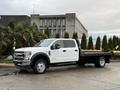 A white 2022 Ford F-550 pickup truck with a flatbed parked on a concrete surface