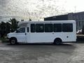 A white 2017 Chevrolet Express shuttle bus with large windows and a rounded roofline parked on a street