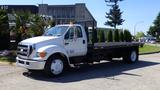 A 2006 Ford F-650 truck with a flatbed and metal rack on the back parked on a concrete surface