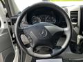 Interior view of a 2012 Mercedes-Benz Sprinter with a black leather steering wheel featuring the Mercedes logo and dashboard gauges visible in the background