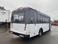 A white 2018 Chevrolet Express bus with large windows and a rear entry is parked, showing its back and side profile