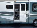 A 2000 Ford Motorhome with a white door open and a set of steps leading up to it featuring a blue and gray exterior design