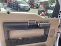 The interior door handle and control panel of a 2014 Ford F-350 SD in tan and black plastic materials