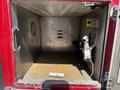 Empty storage compartment of a 2006 Emergency One Fire Truck with a silver hand pump and a connector visible inside