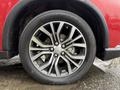 A close-up of a 2016 Mitsubishi Outlander wheel featuring a multi-spoke alloy rim and a Geolandar tire with visible tread and water droplets on the surface
