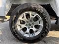 Close-up of a silver alloy wheel from a 2021 Ford F-150 featuring Goodyear Wrangler tire with bold white lettering on the sidewall and visible lug nuts