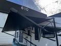 A 2022 Heartland Torque recreational vehicle with a black awning extended and a detailed exterior design