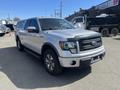 A silver 2014 Ford F-150 with a black front grille and a truck bed cover parked on a paved surface