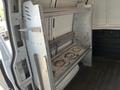 A metal shelving unit inside a 2014 Chevrolet Express van designed for storage with two shelves and visible wear and tear