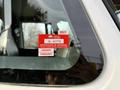 A red and white certificate of approval sticker affixed to the window of a vehicle displaying various details like an expiration date and month labels